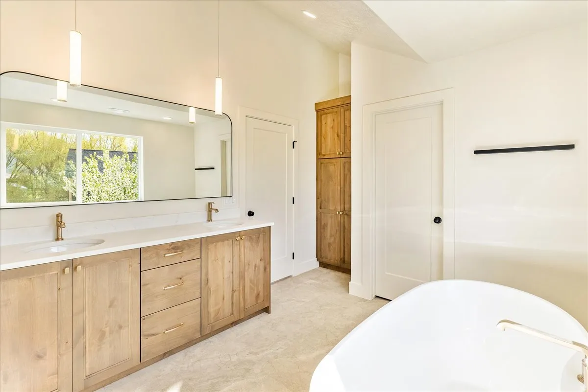 Bathroom featuring a double vanity with wood-finish cabinetry, white countertops, and dual vessel sinks