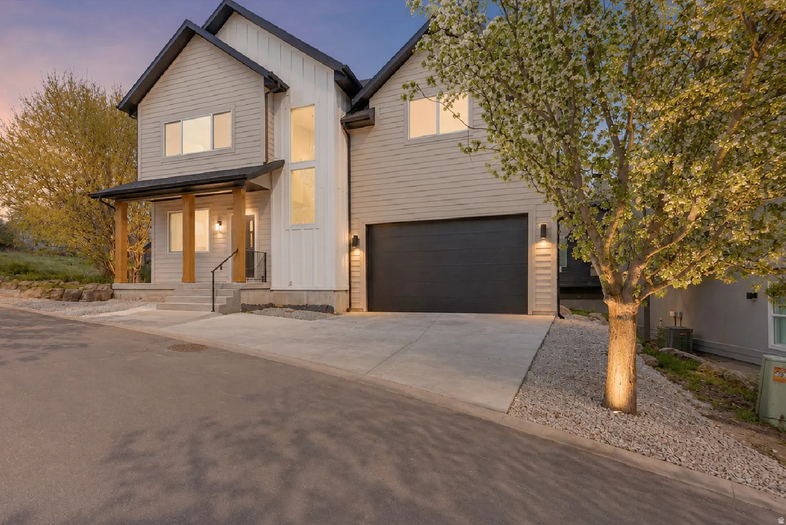 Modern facade with light-toned siding, dark trim, and prominent entryway featuring wood columns