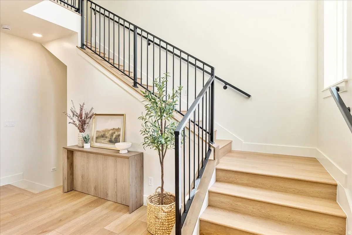Hardwood staircase featuring black metal railings and a continuous handrail