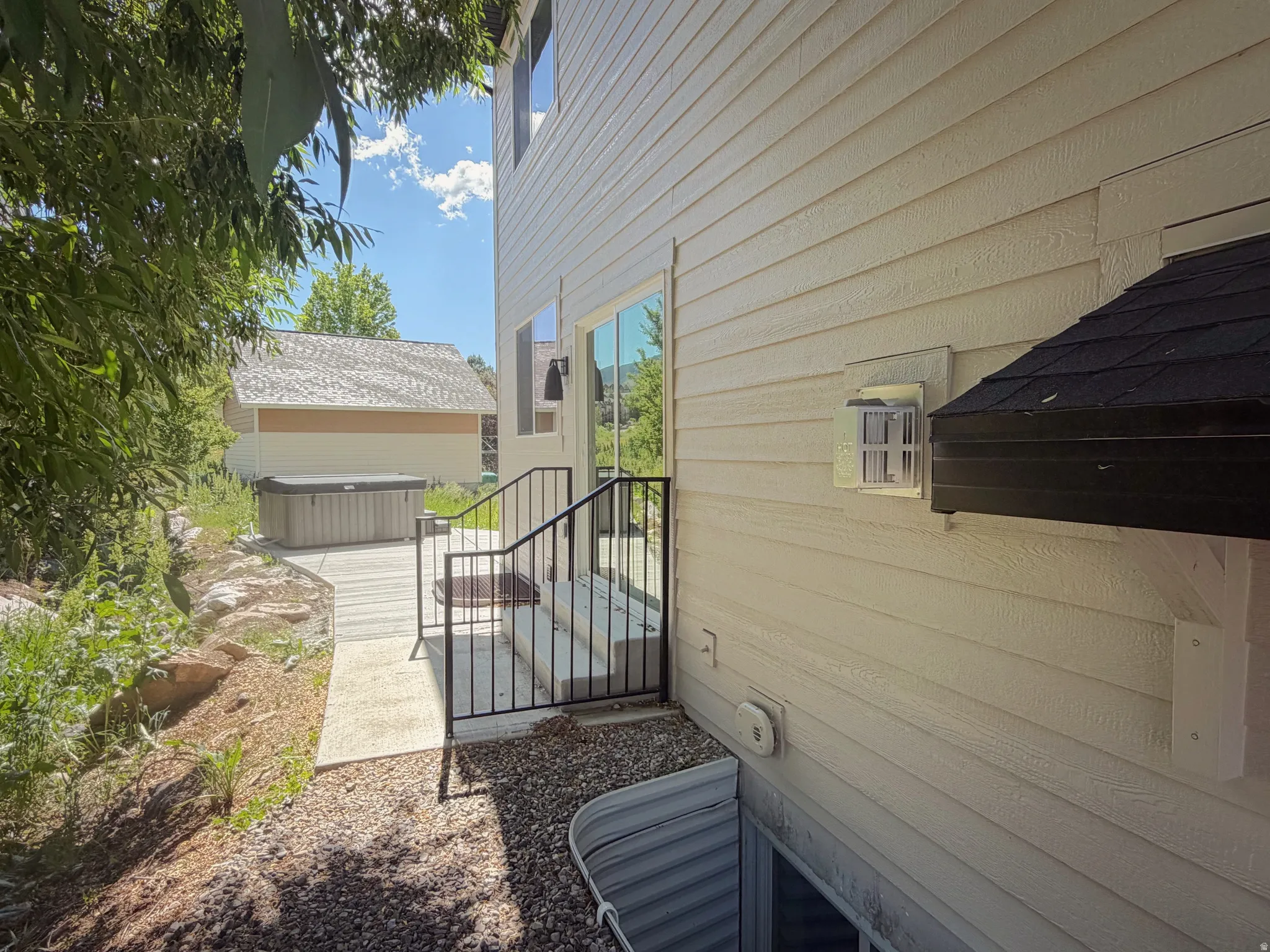 Exterior siding in a neutral tone with a contrasting black pitched roof over an outdoor fixture