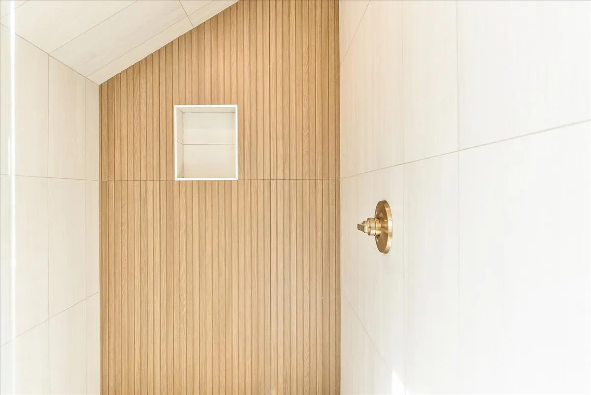 Shower enclosure featuring a wood-panel accent wall and light-toned tile