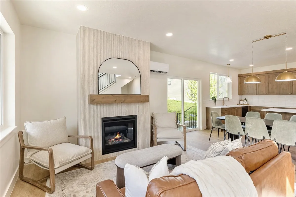 Living space featuring a gas fireplace with a wood mantle and textured surround, recessed lighting, and wood-finish flooring