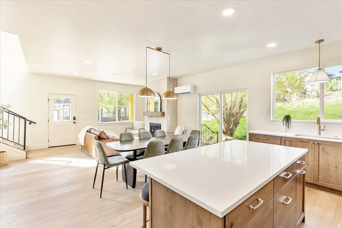Open-concept living space featuring wood-finish flooring, a kitchen island with a light-toned countertop, and integrated ceiling lighting