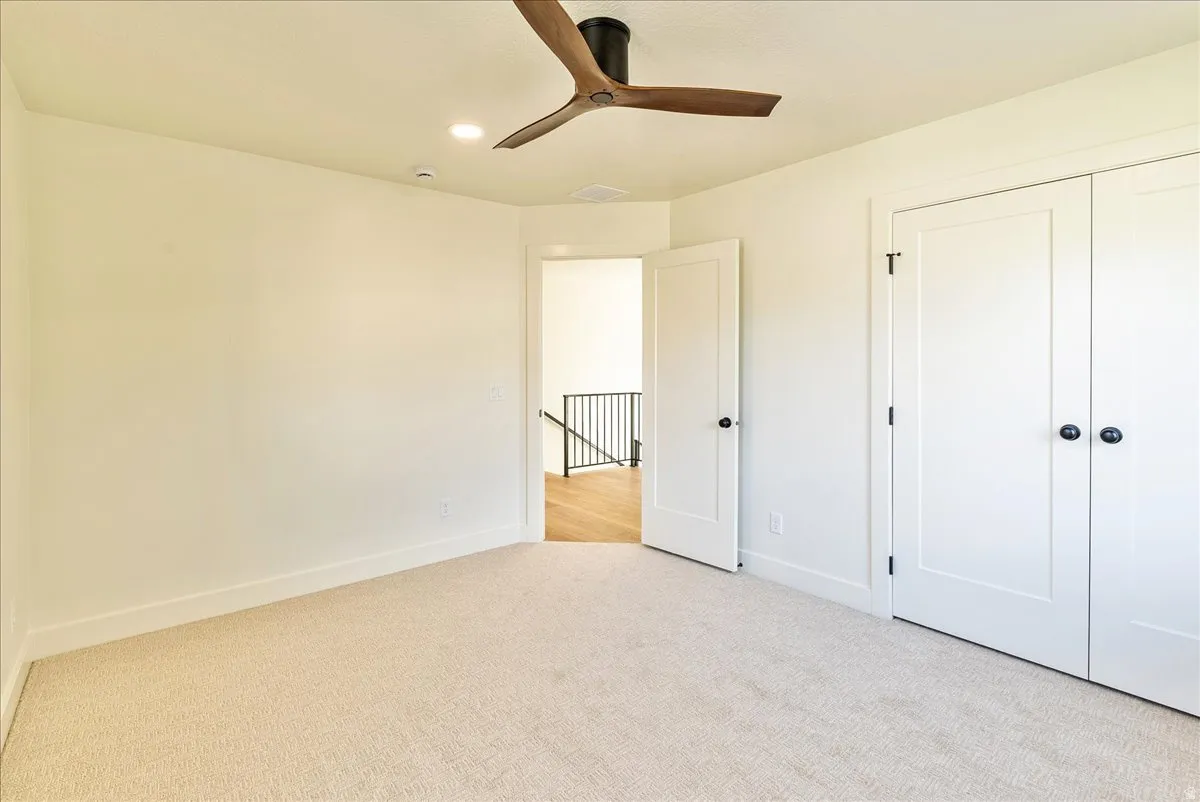 Neutral tone wall color, recessed lighting, and a modern ceiling fan