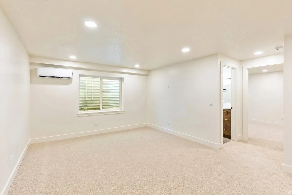 Cream-toned carpeting in a spacious room featuring a window with security grating