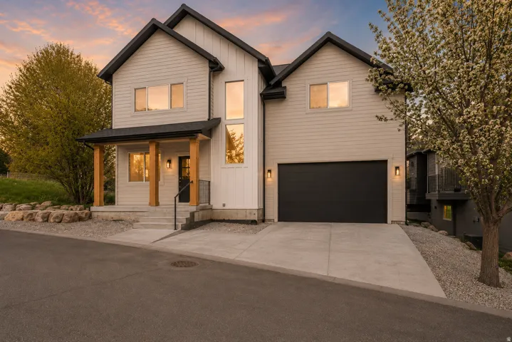 Modern two-story residence featuring a black gabled roofline, light-toned horizontal siding, and vertical board and batten accents
