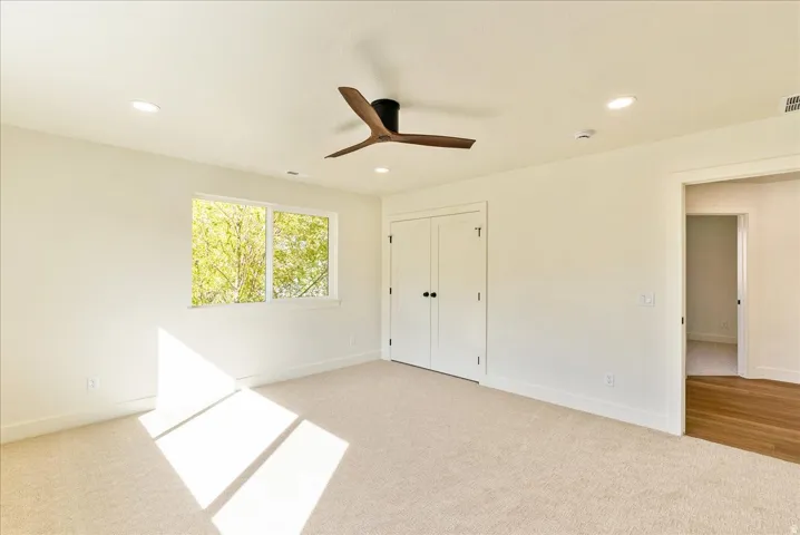 Spacious room featuring carpeted flooring, a ceiling fan with integrated lighting, recessed lighting, and a double-door closet
