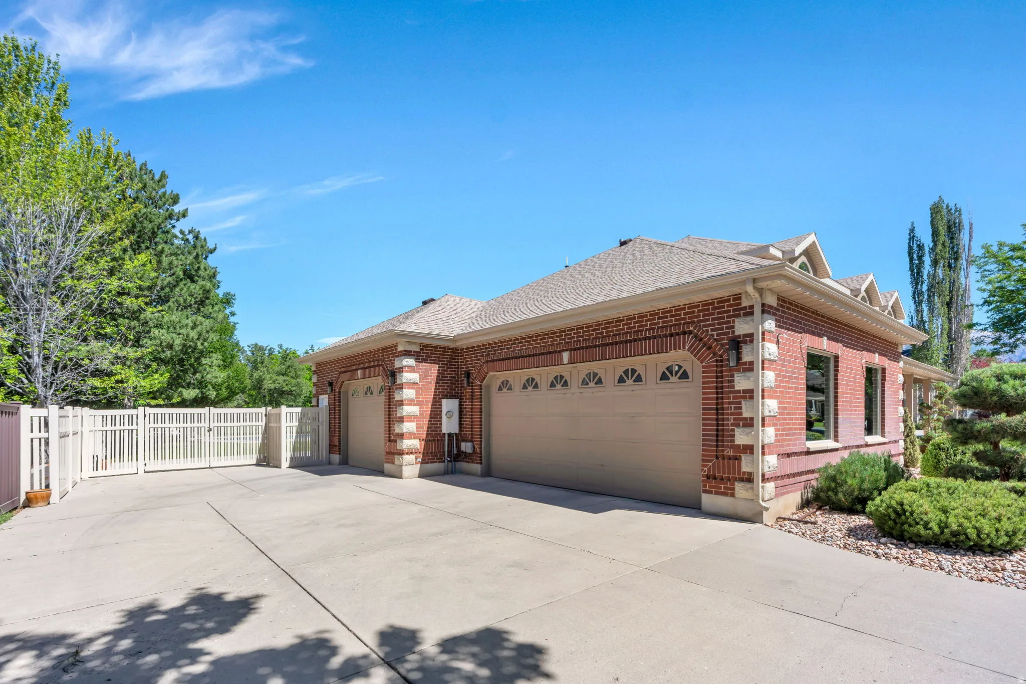 Brick exterior featuring two beige garage doors and decorative white trim