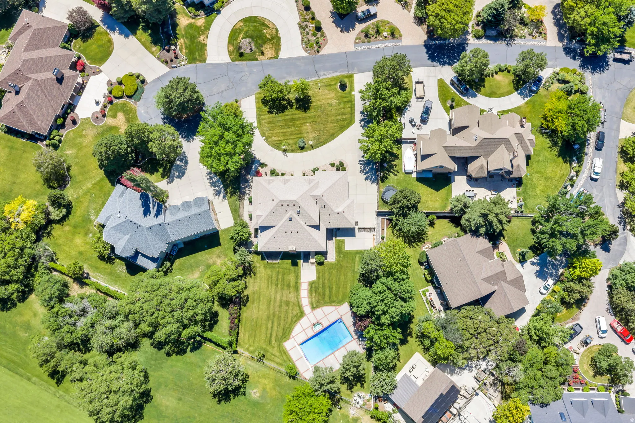 Expansive property featuring a multi-level roofline, extensive green landscaping, and a rectangular swimming pool