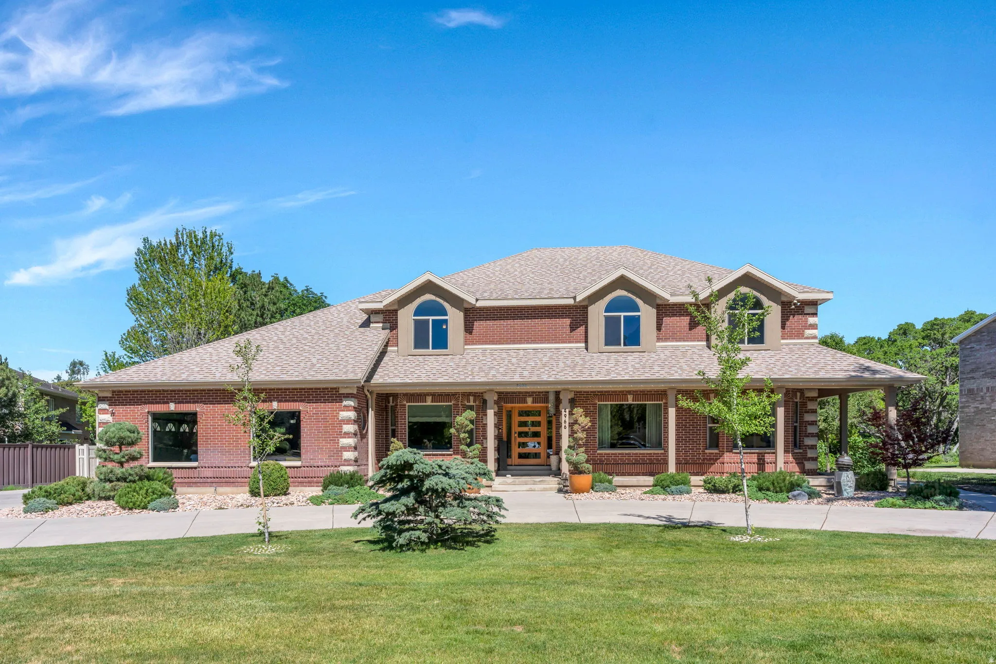 Expansive brick exterior with a substantial shingle roof and a covered front porch