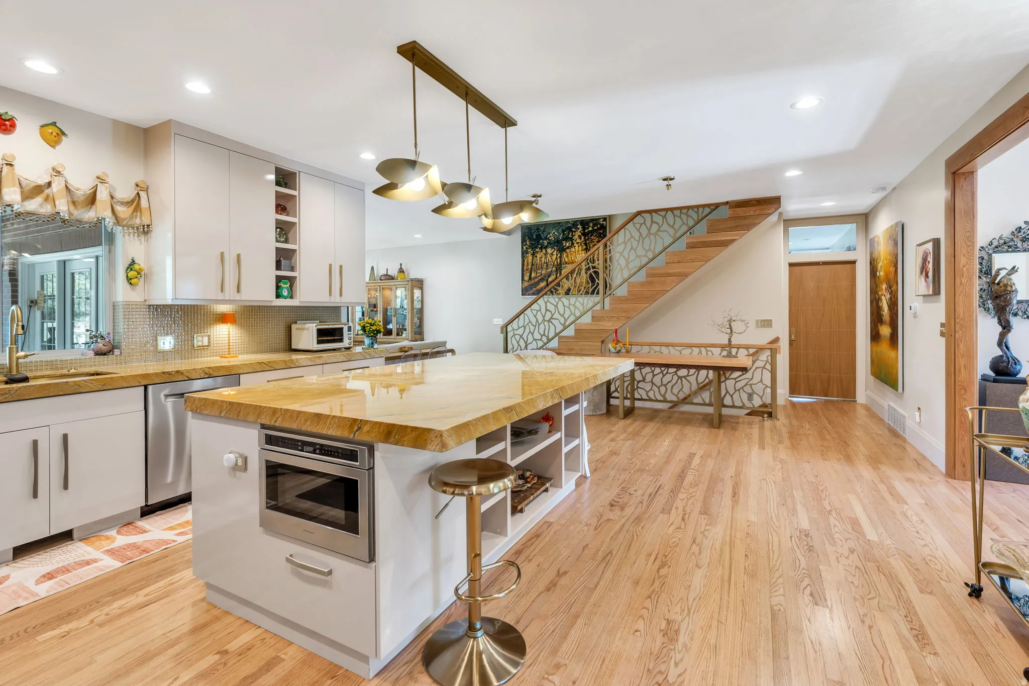 Open-concept kitchen featuring light-toned cabinetry, a large center island with a wood-finish countertop, and stainless steel appliances