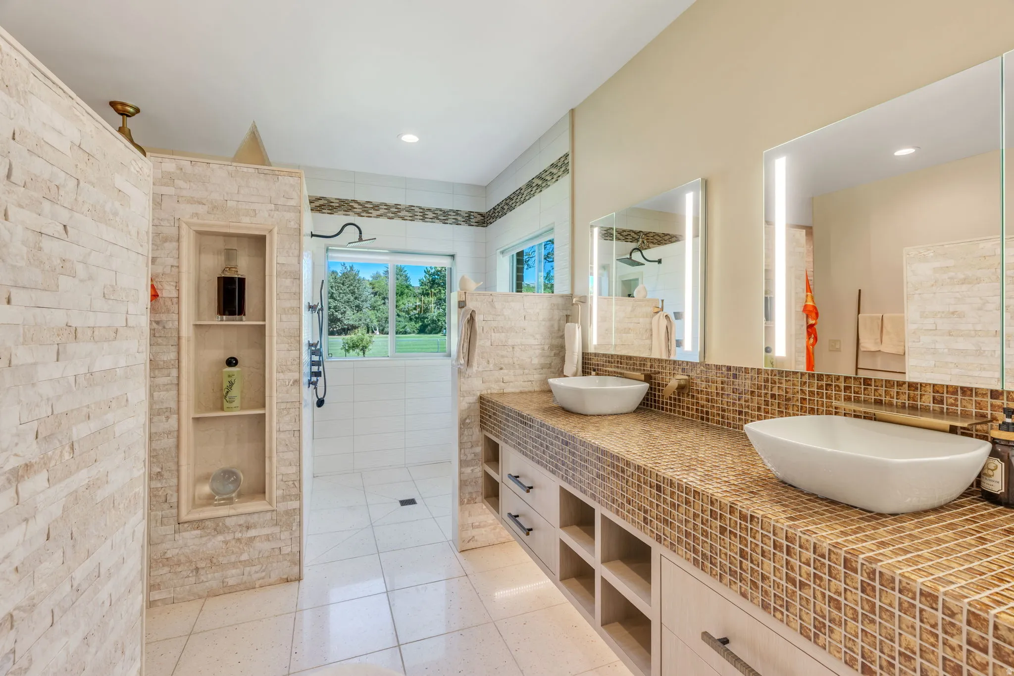 Dual vessel sinks set atop a mosaic-tiled vanity with integrated storage