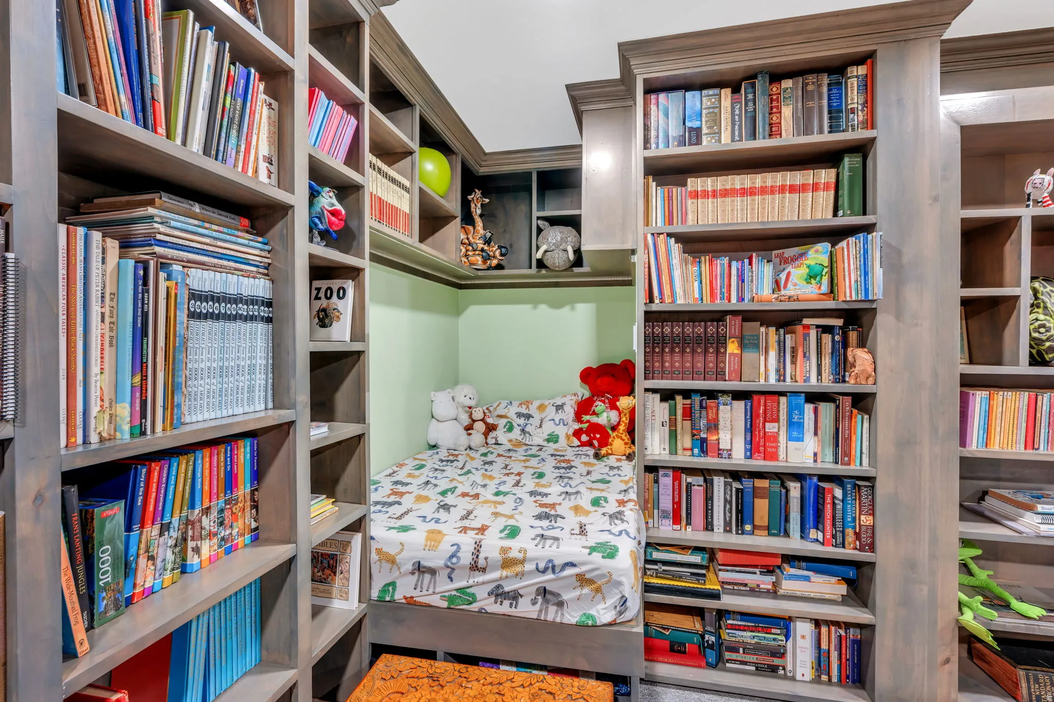 Built-in shelving units in a natural wood finish frame a recessed sleeping alcove
