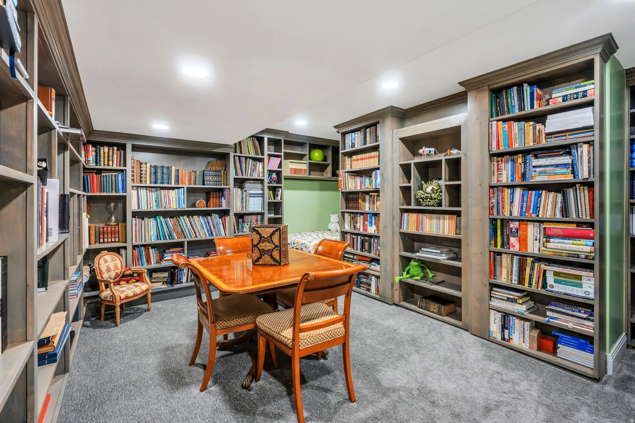 Dedicated library space featuring extensive built-in shelving, recessed lighting, and soft carpet flooring