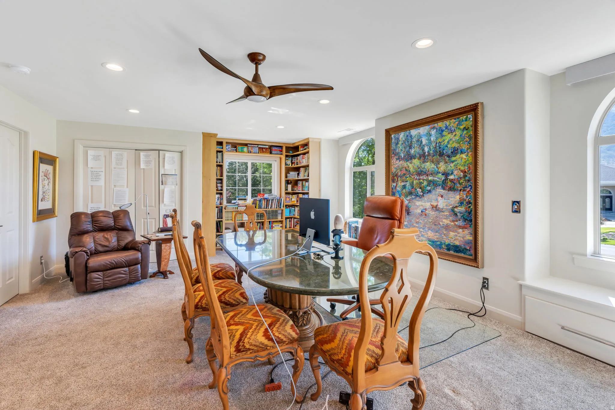 Spacious room featuring a corner built-in bookcase, recessed lighting, and arched windows
