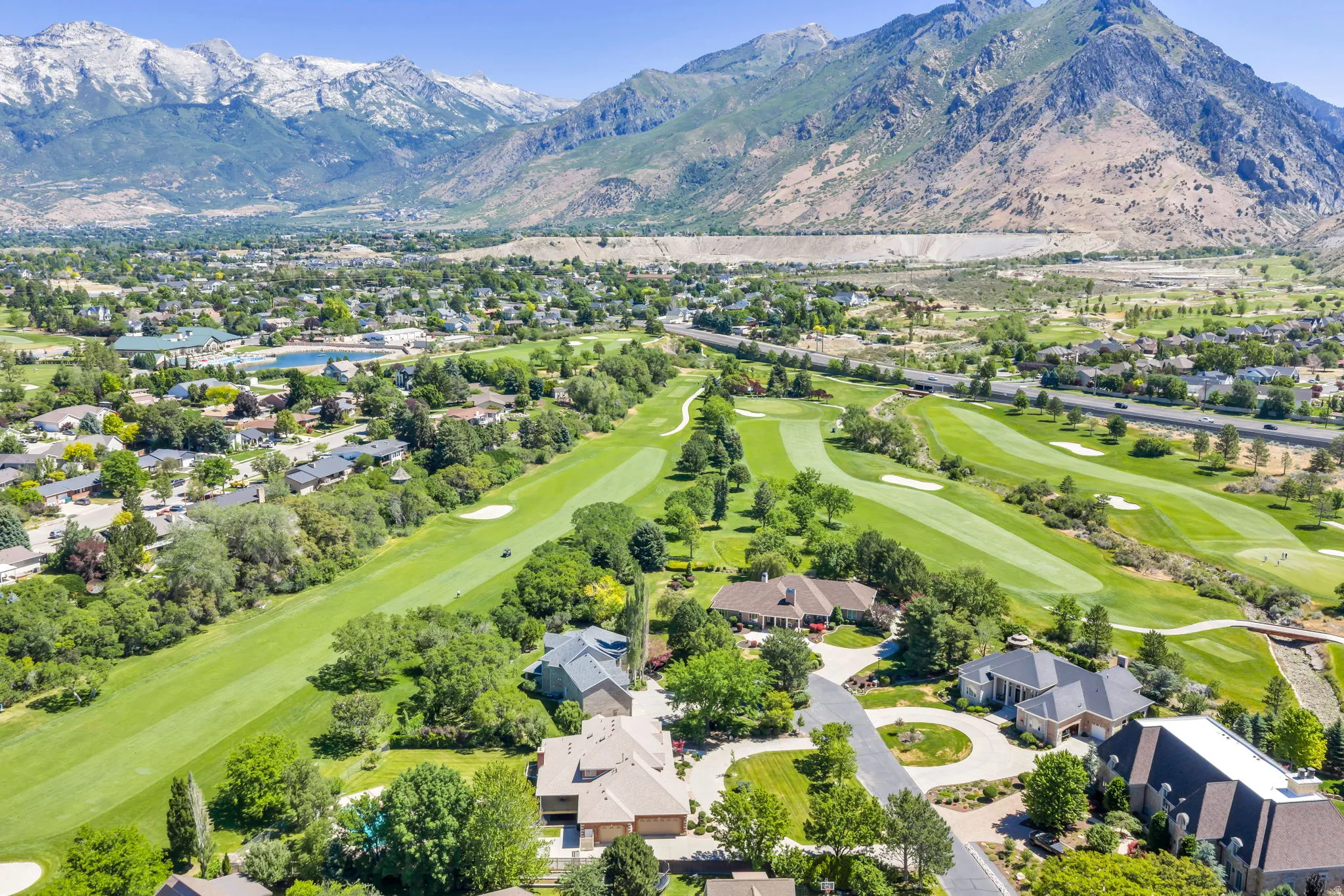 Expansive residential area featuring a golf course, mature trees, and mountainous terrain