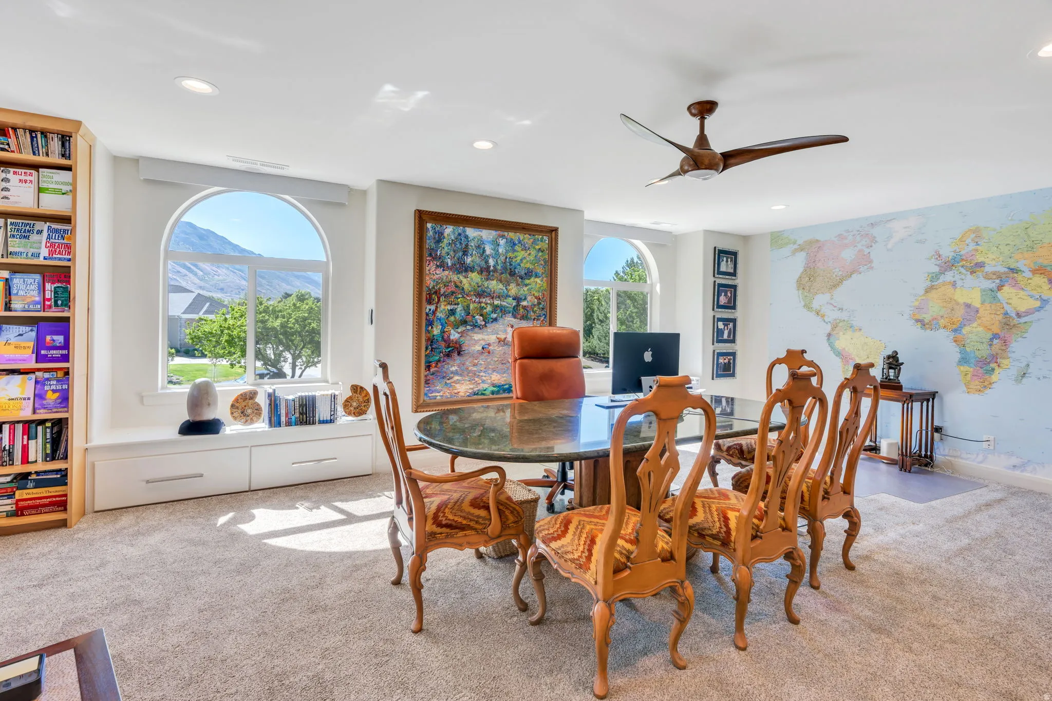 Office space featuring arched windows, built-in window seating with drawer storage, a built-in wooden bookshelf, recessed lighting, and a ceiling fan