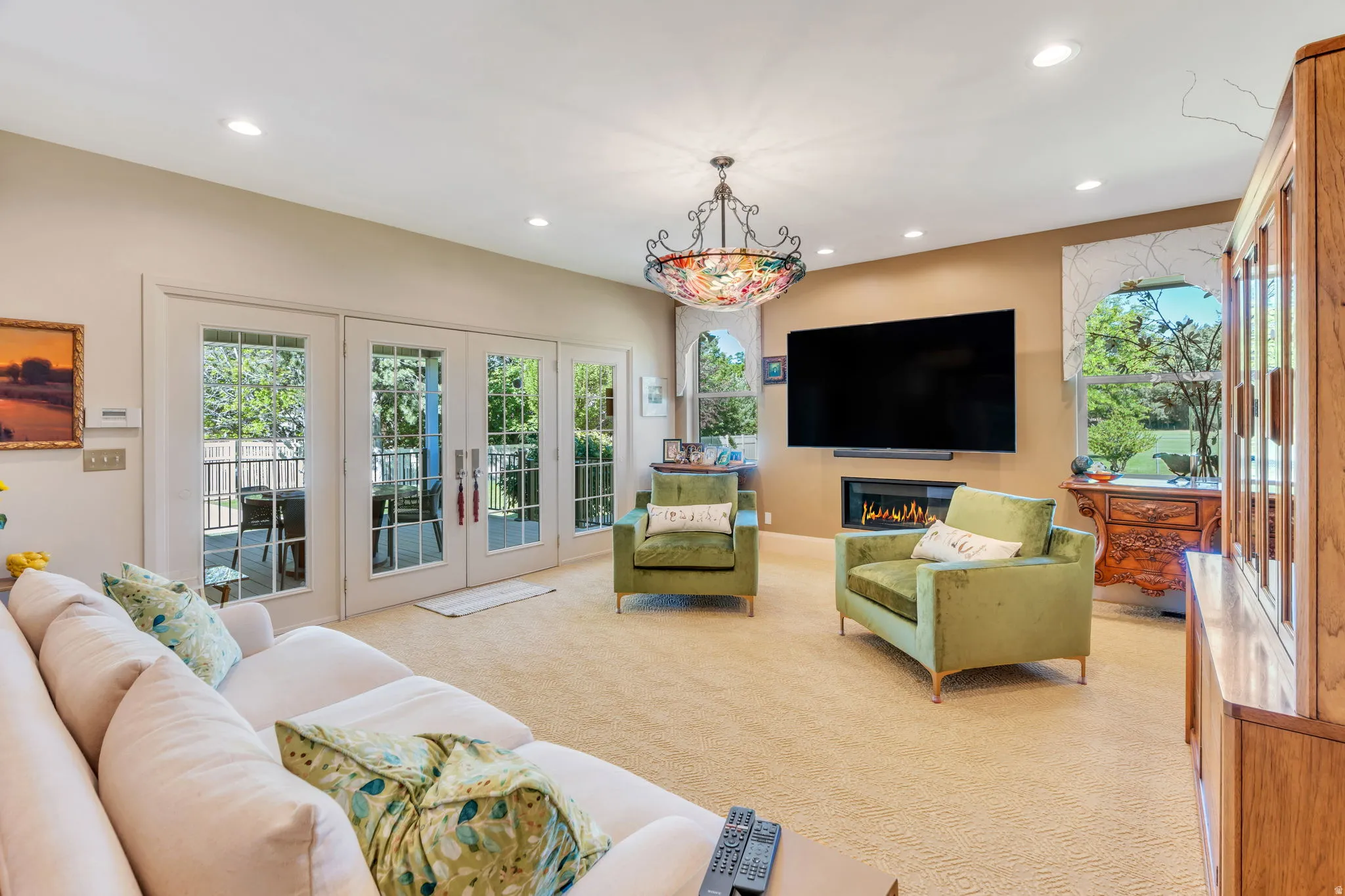 Living space featuring multiple sets of glass-paneled French doors, recessed lighting, and a decorative ceiling fixture
