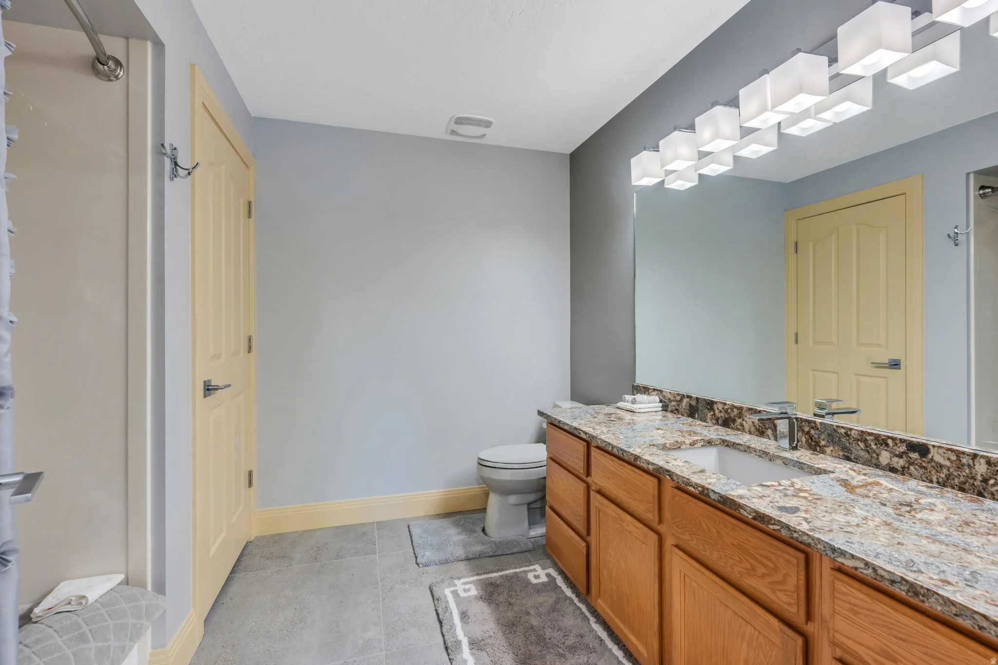 Bathroom vanity featuring a single undermount sink, a chrome faucet, and a stone countertop