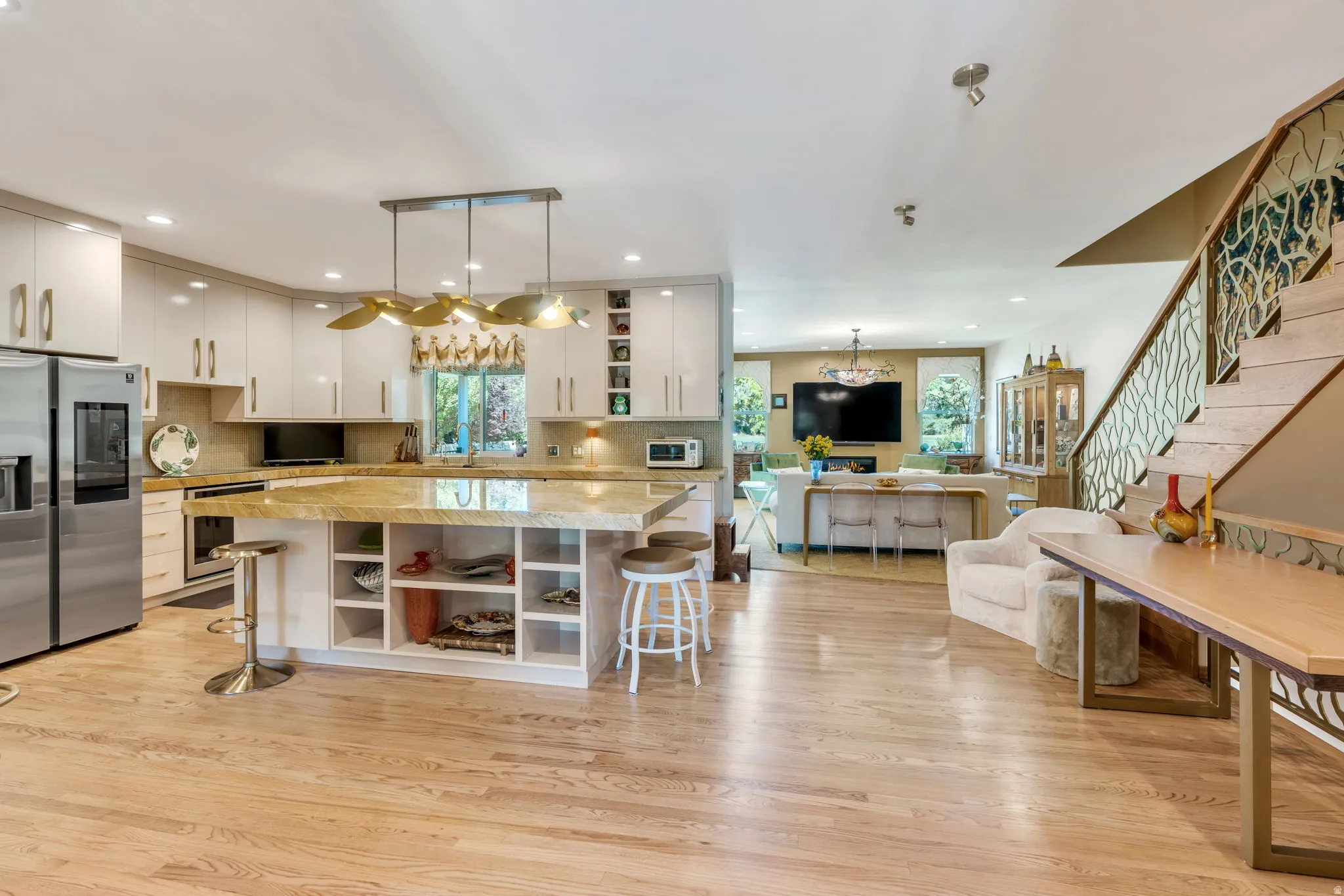 Open-concept living space with wood-finish flooring, a contemporary kitchen, and a custom staircase