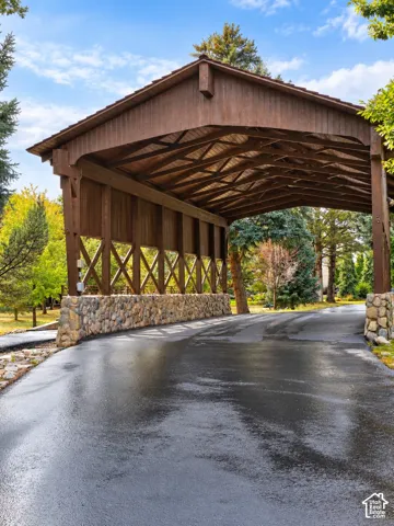 Covered entry structure with a stone base, wood-paneled exterior, and exposed wood ceiling beams