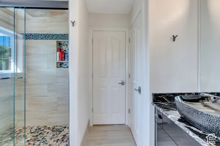 Bathroom featuring a glass-enclosed shower with pebble-tile flooring, a recessed shower niche, and light-toned wall tiling