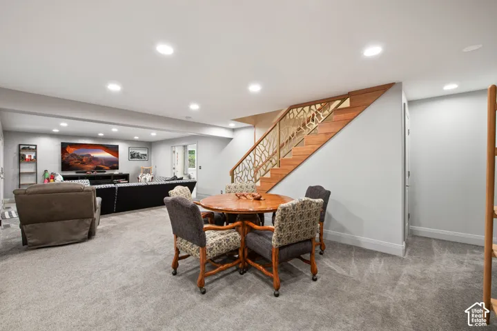 Recessed lighting, wood-finish staircase with decorative metal railing, light gray wall paint, and gray carpeted flooring