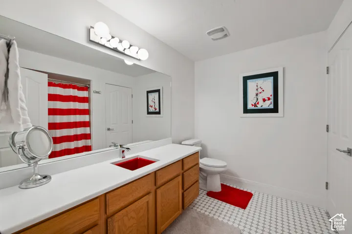 Dr. Suess theme bathroom. Extended vanity with wood-finish cabinetry, white countertop, and red vessel sink