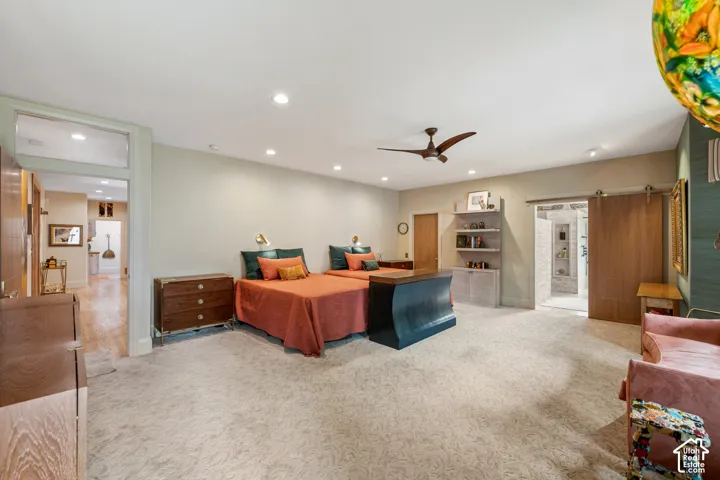 Recessed lighting illuminates a spacious room featuring wall-to-wall carpeting and a ceiling fan