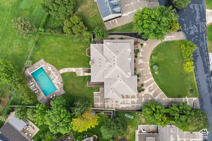Spacious property featuring a large house with a multi-gabled roof, an expansive lawn, a swimming pool with an integrated spa, and a curved driveway