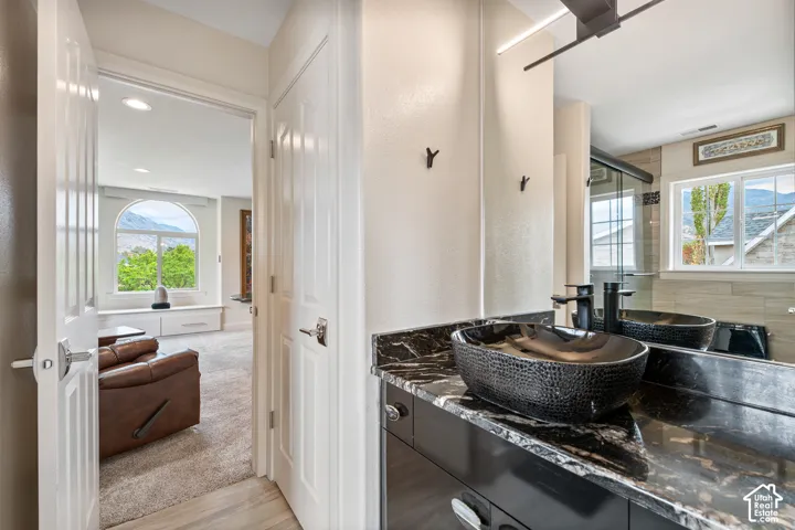 Bathroom vanity with a black vessel sink, dark countertop, and large mirror