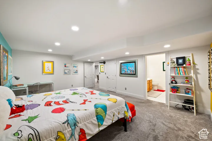 Large basement bedroom in Dr. Suess decor with ensuite. plush carpeting, and an attached bathroom with vanity and white tile flooring