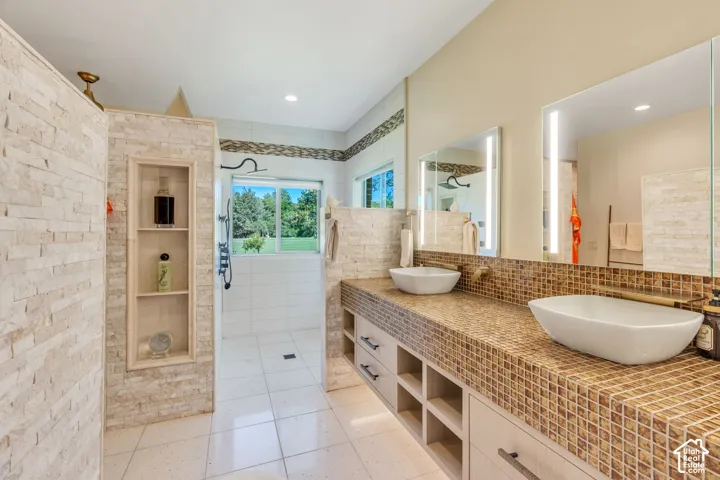 Dual vessel sinks set atop a mosaic-tiled vanity with integrated storage