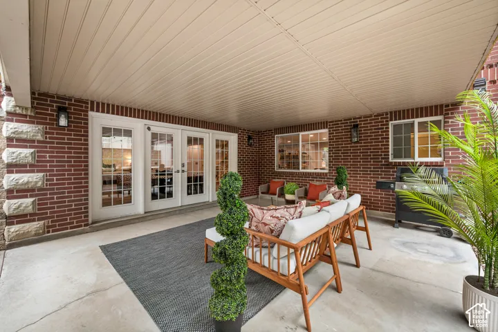 Basement covered patio featuring a brick exterior with stone accents, a concrete floor, and multiple window-pane doors