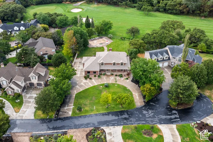 Expansive property featuring a circular driveway, mature landscaping, and a substantial private pool