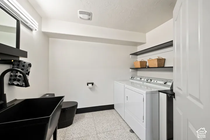 Basement laundry and half bath. Black basin sink with a wall-mounted faucet, black toilet, and a black-framed mirror