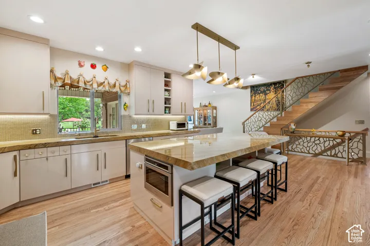 Kitchen featuring hardwood flooring, a central island with integrated oven, and overhead lighting