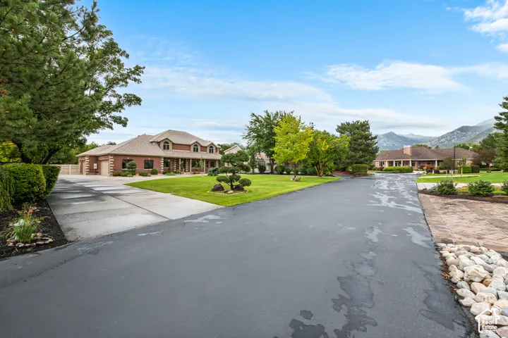 Brick exterior residence with a dormered roofline, a multi-car garage, and a concrete driveway