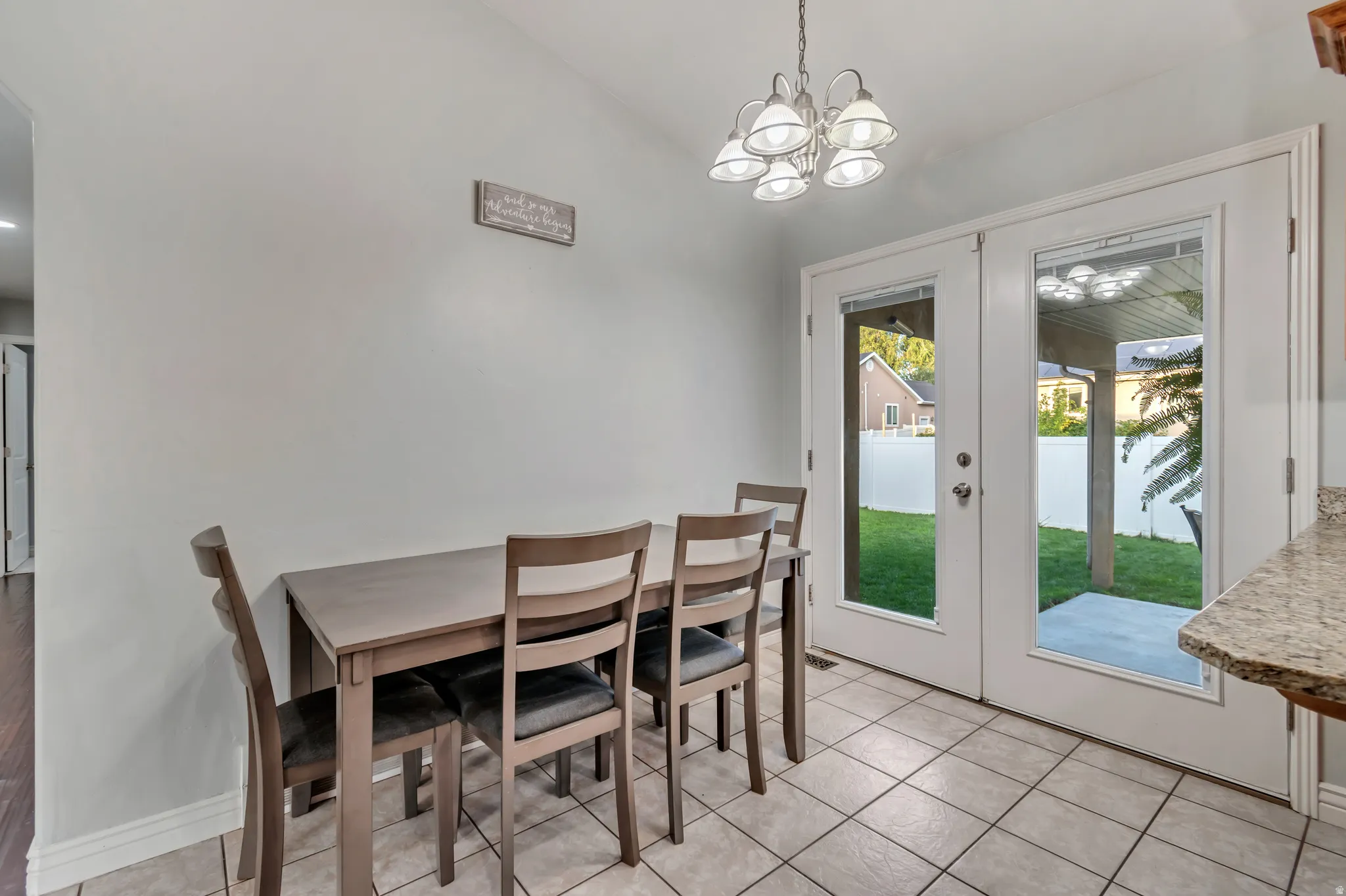 Dining area featuring light tile flooring and a five-light chandelier
