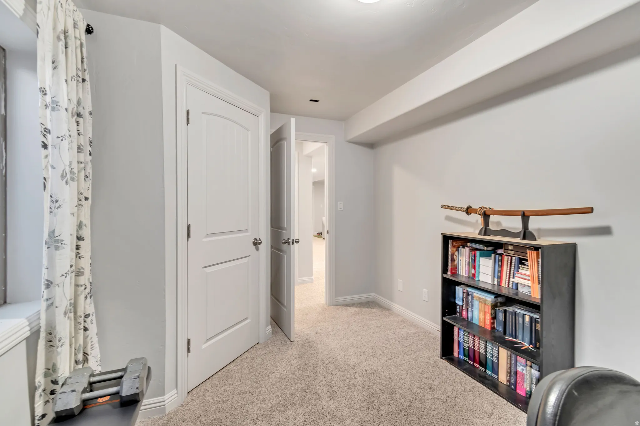 Carpeted room with a window featuring a deep sill, white trim, and a white interior door