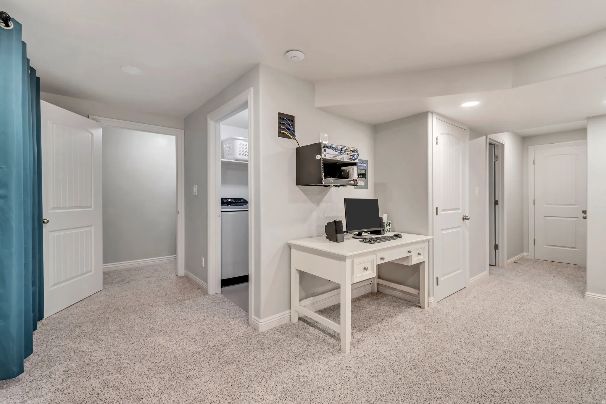 Versatile finished basement space with neutral carpeting and recessed lighting
