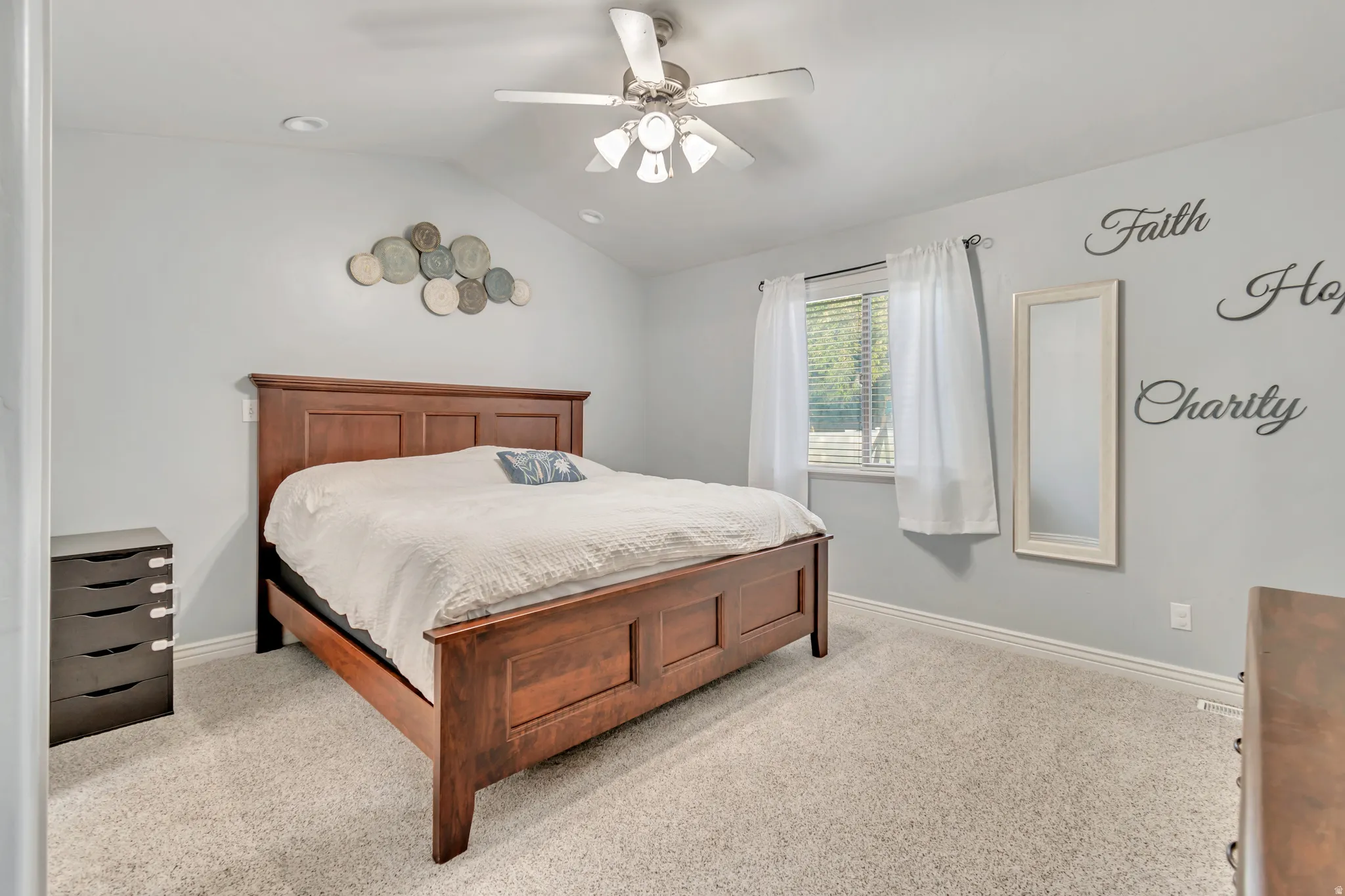 Carpeted bedroom featuring a vaulted ceiling and a ceiling fan with integrated lighting