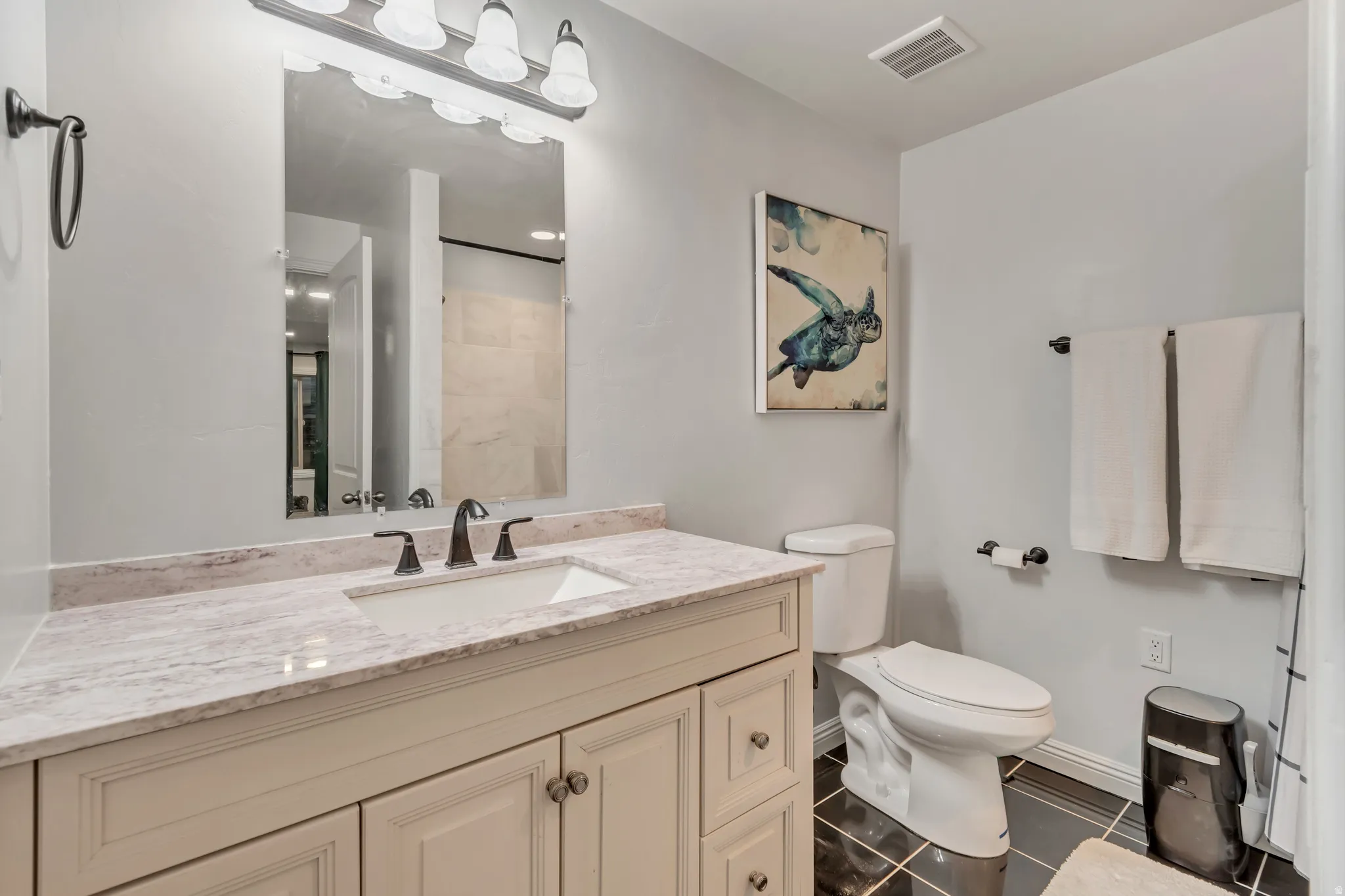 Bathroom featuring a single vanity with integrated sink, stone countertop, and custom cabinetry