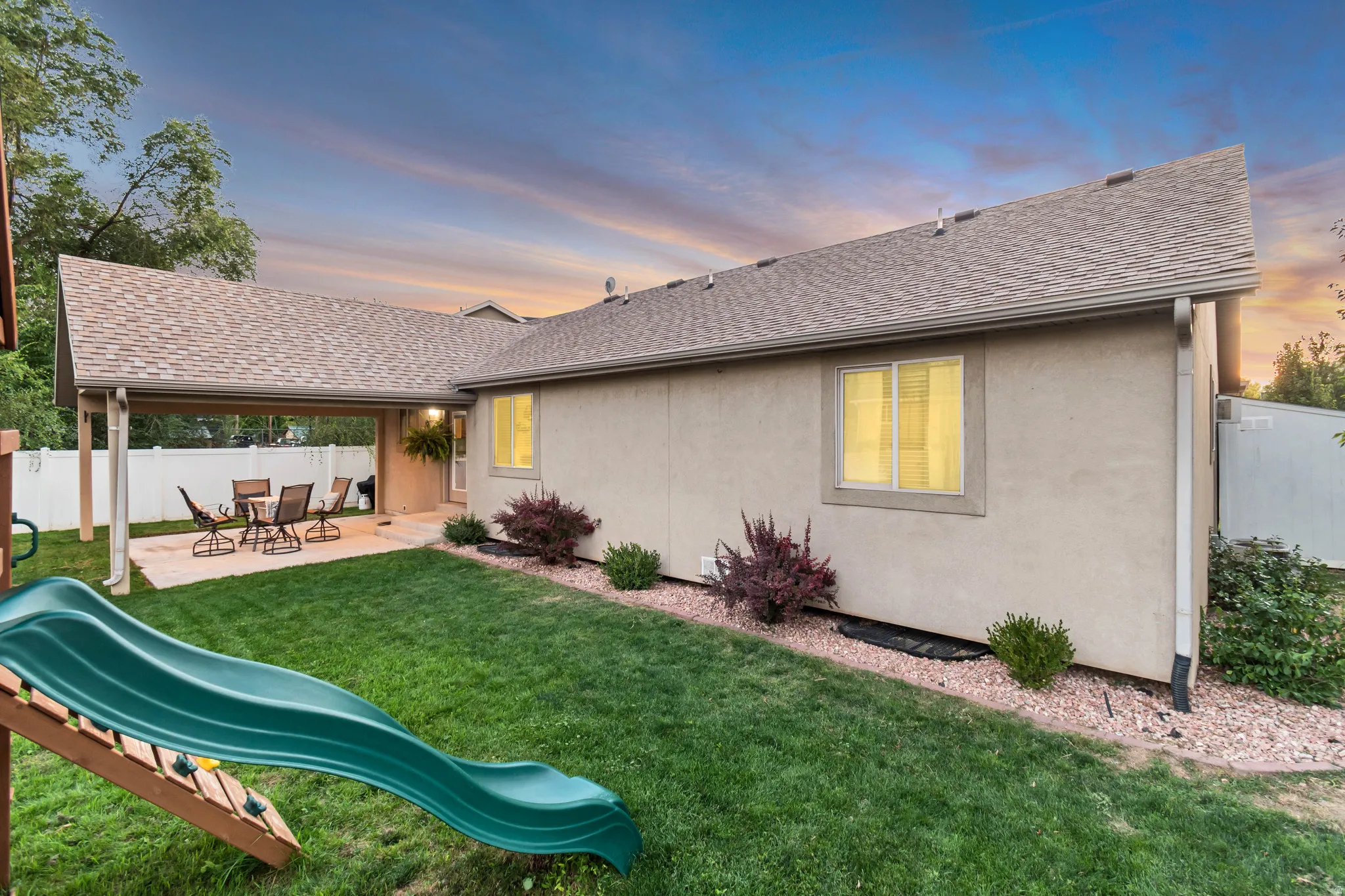 Expansive backyard featuring a covered patio, manicured lawn, and low-maintenance landscaping