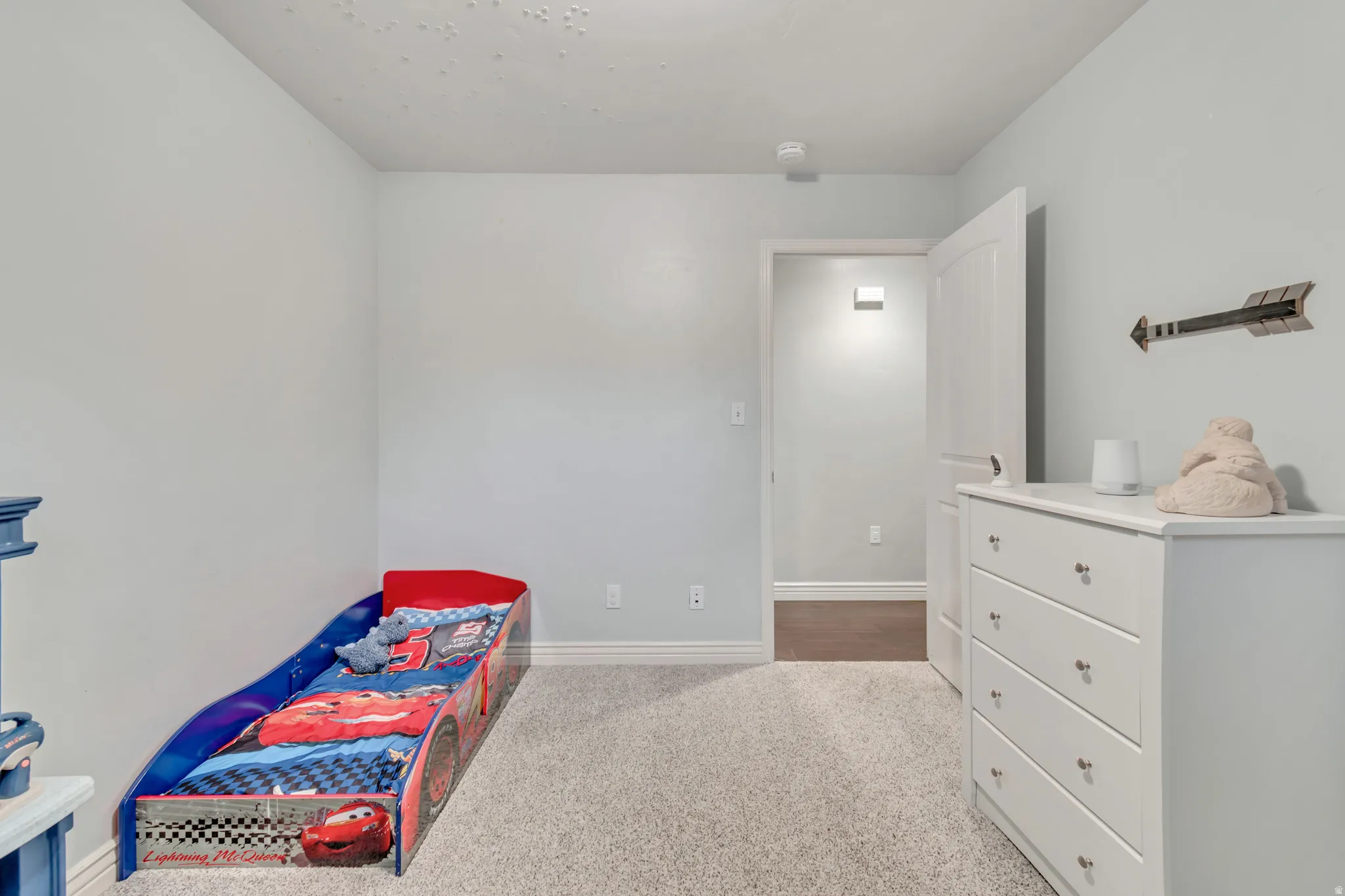 Carpeted room featuring light blue painted walls, white baseboards, and a white interior door with a silver knob