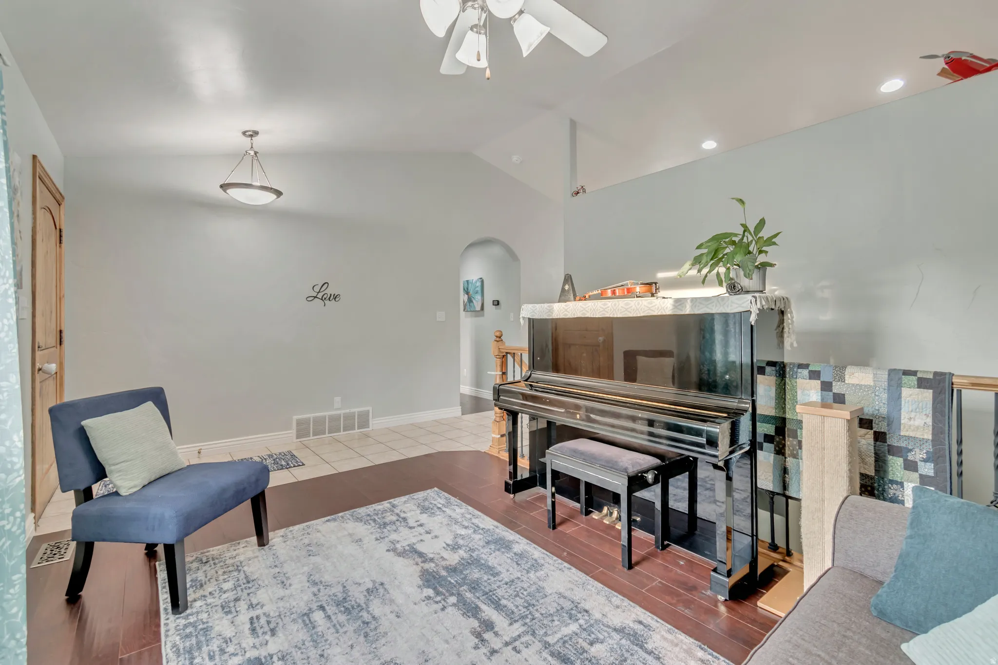 Vaulted ceiling room featuring rich wood-finish flooring and light-toned walls