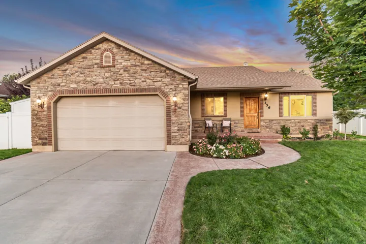 Stone and stucco exterior featuring a two-car garage, concrete driveway, and a curved stamped concrete walkway leading to the front entry