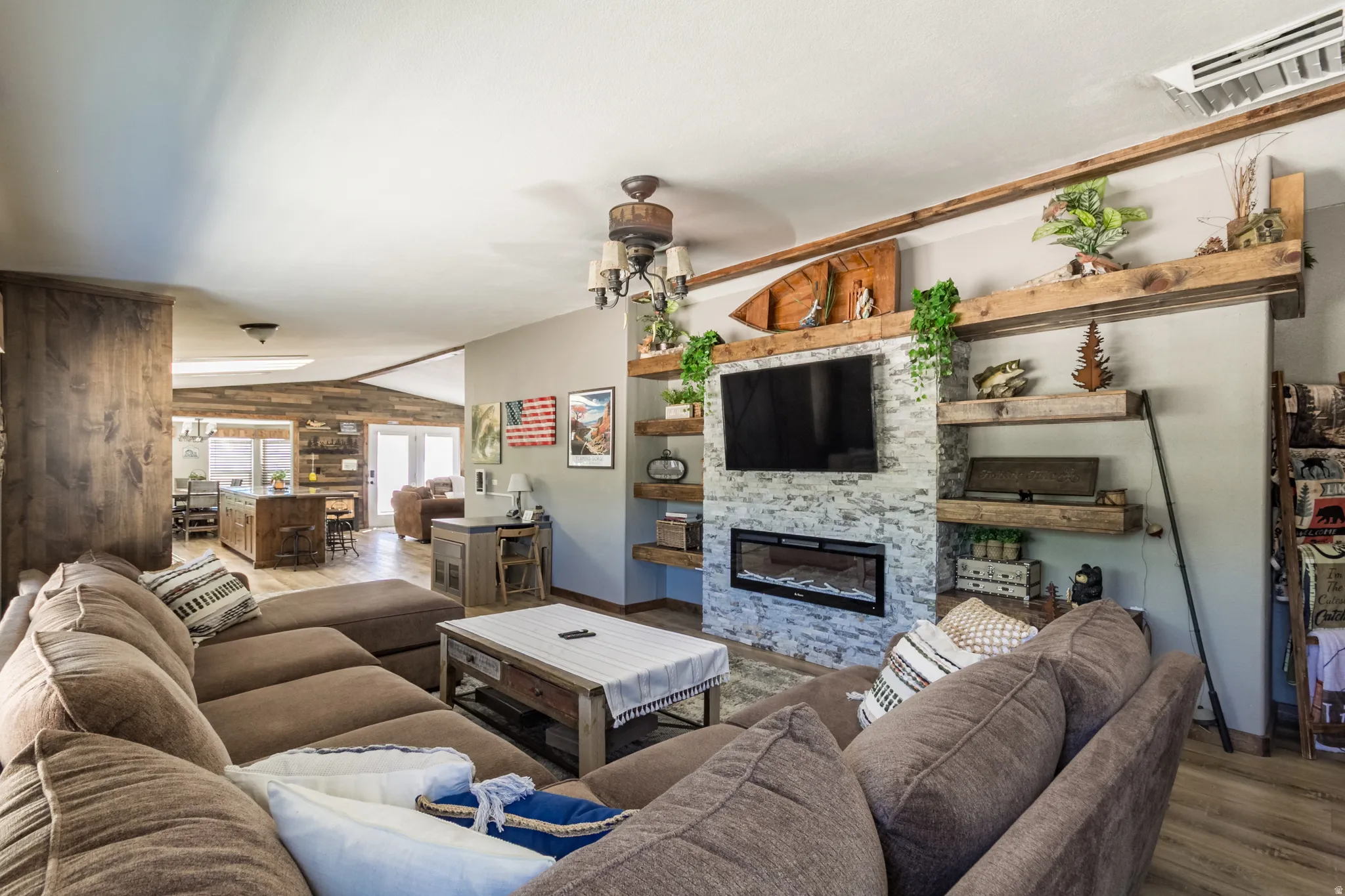 Living area featuring a stone-clad fireplace with an integrated electric insert, wood-finish flooring, recessed lighting, and a ceiling fan