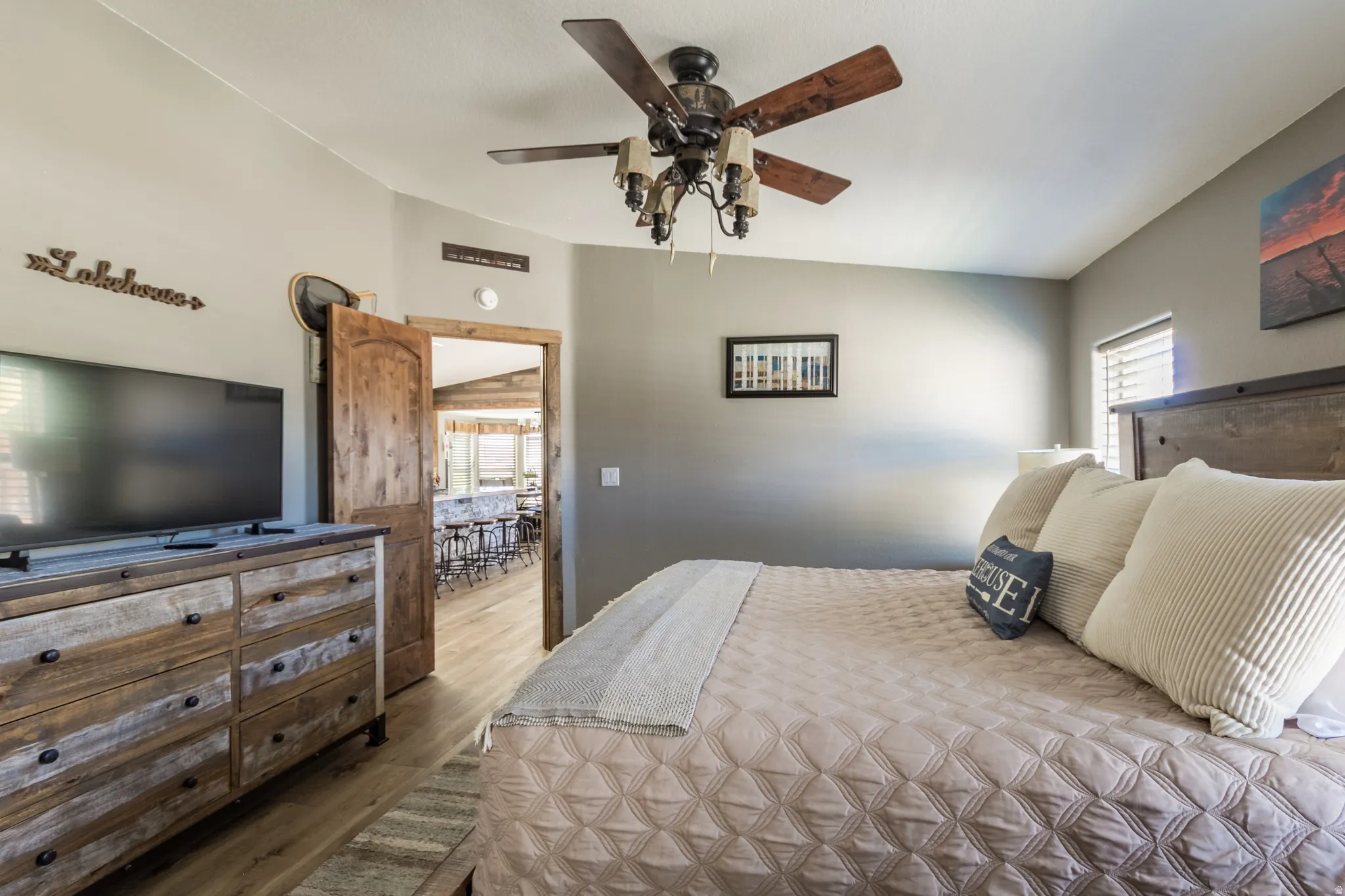 Interior room featuring wood-finish flooring, a rustic wood doorframe, and a wood-bladed ceiling fan with integrated lighting
