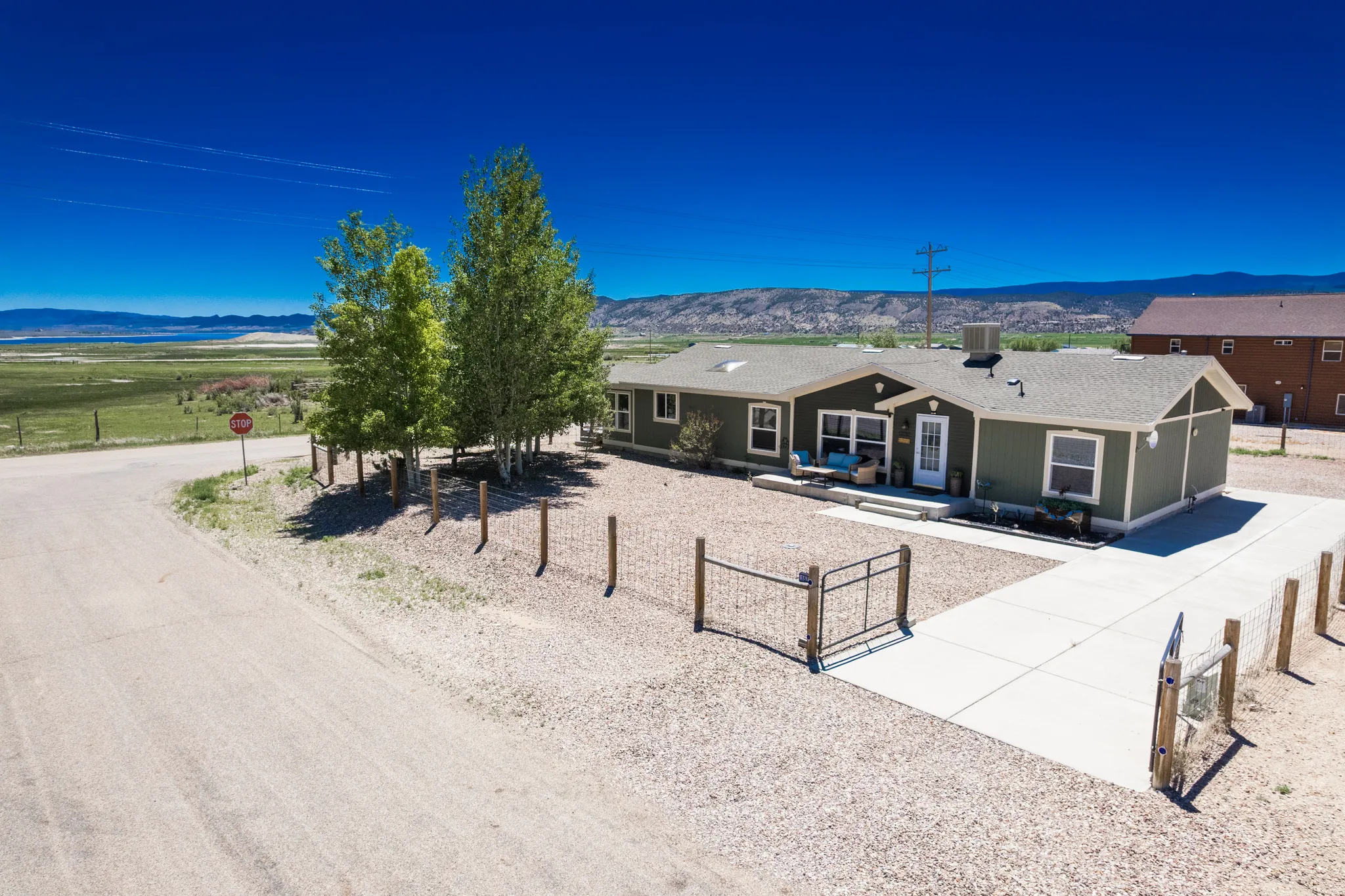 Ranch-style residence featuring a dark green exterior, a light-colored concrete driveway, and a gravel yard